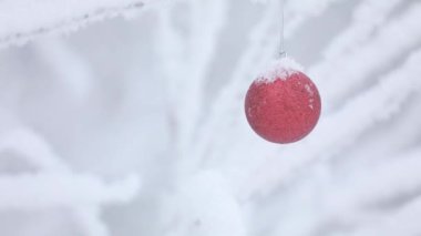 Yeni yıl. Noel ve süslemeler. Kırmızı bir oyuncak Noel Baba ormanda bir dalı sallanıyor. Kar yağışı