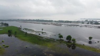 Suyun alçalmasından sonra bir hidroelektrik santrali tarafından nehre döküldü. Çayır taşkınları. Nehir kıyıları boyunca yeşil ağaçlarla