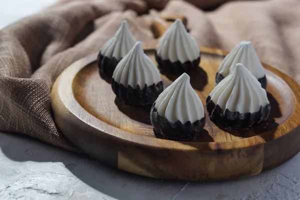 Koyu ahşap bir tahtanın üzerinde çikolata kaplı kremalar ile nefis bir tatlı tepsisi.