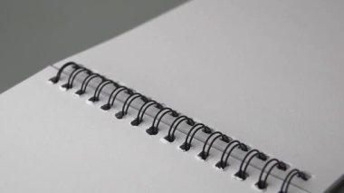 Siyah kablo bağlayıcı ve boş beyaz sayfalar ile açık spiral defterin yakın plan, notlar, çizim veya planlama için hazır, yeni fikirleri ve yaratıcılığı sembolize eden, 60 fps yumuşak odak ve yavaş çekim