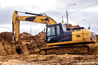 sarı Ekskavatör kum, bulutlu havalarda yol yapım üzerinde çalışma