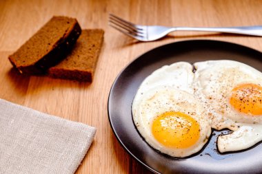 iki yumurta karabiber ahşap masa üzerinde siyah plaka ile kızarmış