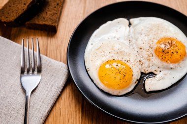 iki yumurta karabiber ahşap masa üzerinde siyah plaka ile kızarmış