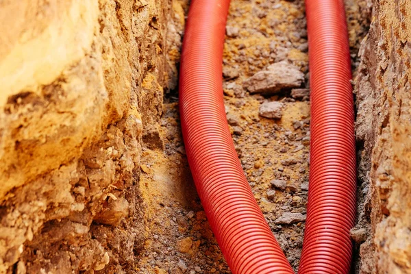 new corrugated PVC pipe for laying electric cable laid in the trench , sandy soil