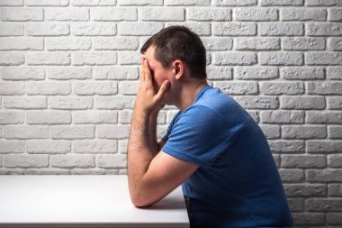 stres adam beyaz masa başında oturup elleriyle başını tutar