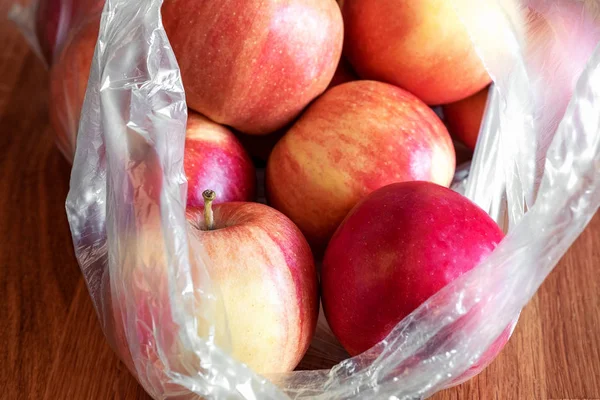 Apple fruit in plastic bag on wood table — Stock Photo, Image