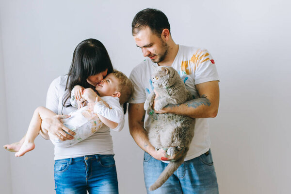 young family with son and cat on a white background after playing with paints