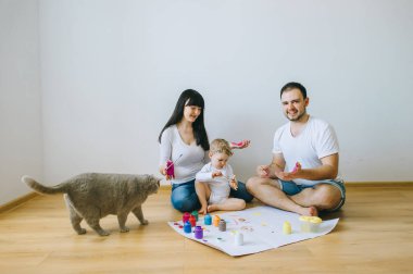 Genç aile evlat ve kedi ile oynadıktan sonra beyaz bir arka plan üzerine boyar