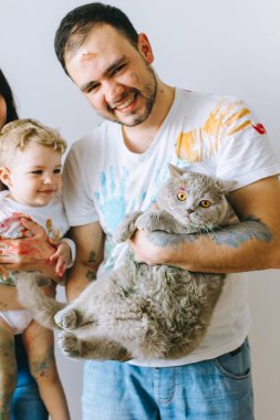 Genç aile evlat ve kedi ile oynadıktan sonra beyaz bir arka plan üzerine boyar
