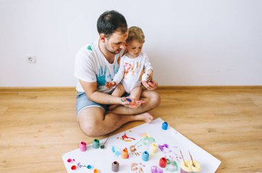 Baba ve çocuğun boya renkleri ile oynuyordu