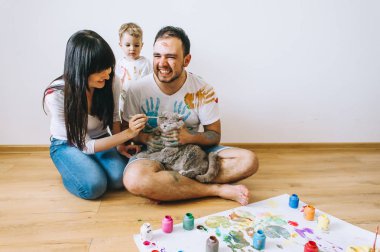 Genç aile evlat ve kedi ile oynadıktan sonra beyaz bir arka plan üzerine boyar