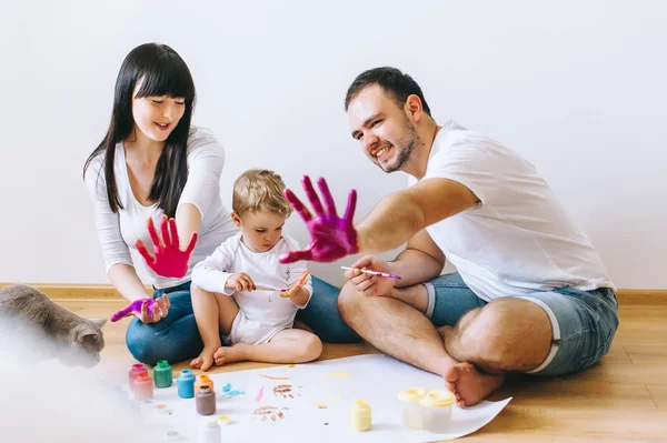 若い家族は息子と遊んで後白い背景の上の猫と塗料します — ストック写真