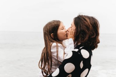 Anne ve kızı elele ve sahilde yürüyüş