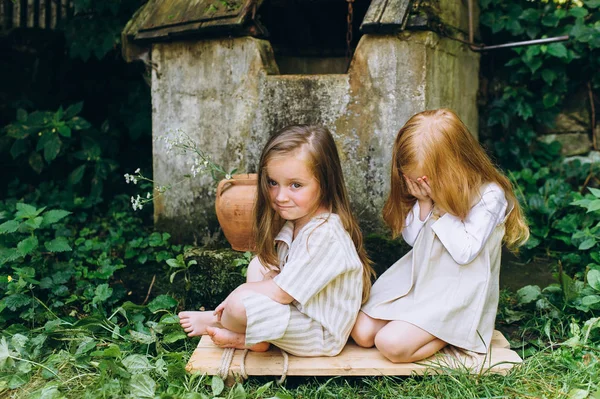 两个漂亮的女孩在古董衬衫附近的井 — 图库照片