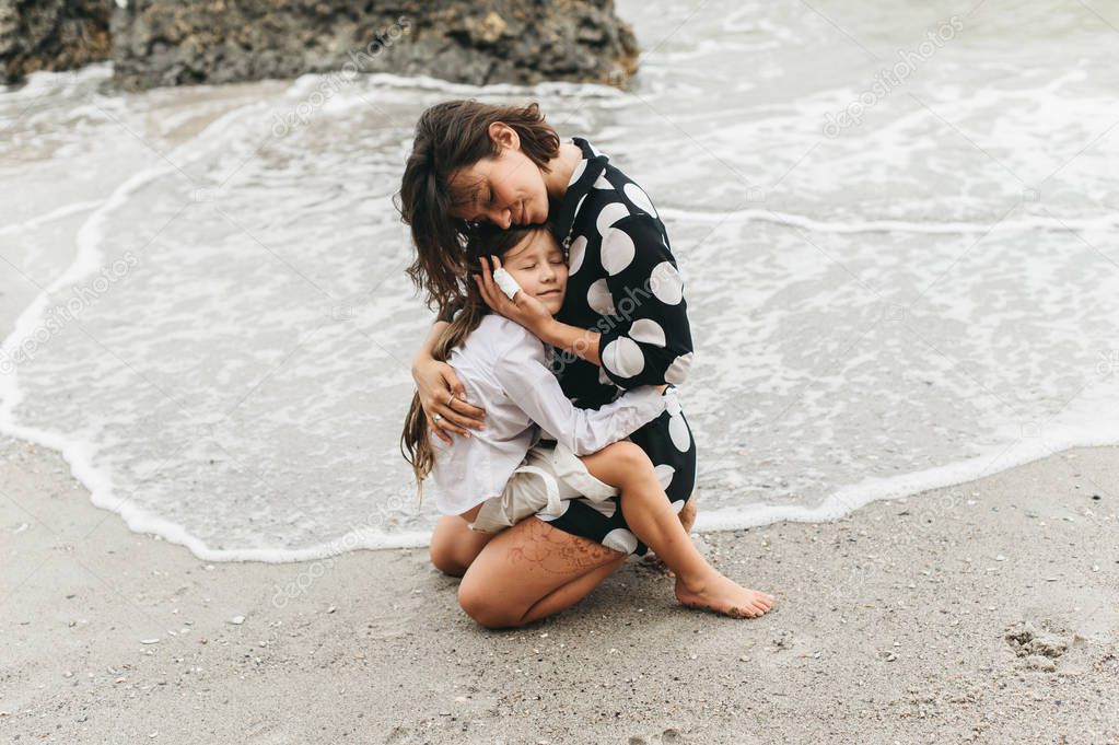 Mother and daughter holding hands and walking on beach