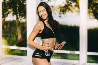 Güneşli yaz gününde egzersiz ve smartphone kullanarak güzel kız