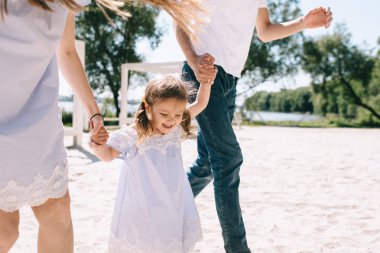 Baba, anne ve kızı eğleniyor ve bir plajda çalışan