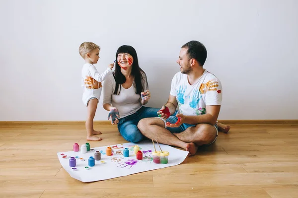 happy father  mother and son show hands in bright colors paint together picture art