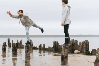 Baba ve oğul bir eğlenceli ve raincoart denize yakın joga exersises işi var.