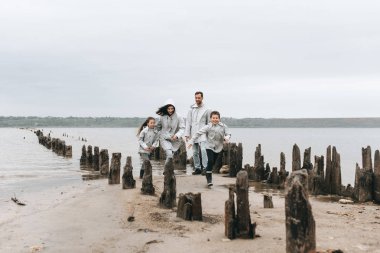 Aile çalışan ve yağmurluk içinde deniz kenarında eğlenin