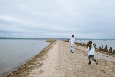 Baba ve koşma yağmurluk giymiş dauther göl yakınındaki ve eğlenceli