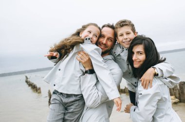 mutlu genç aile bulutlu hava, deniz kenarında eğleniyor