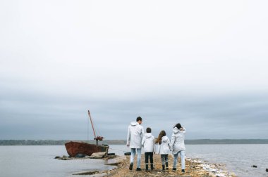 mutlu genç aile bulutlu hava, deniz kenarında eğleniyor