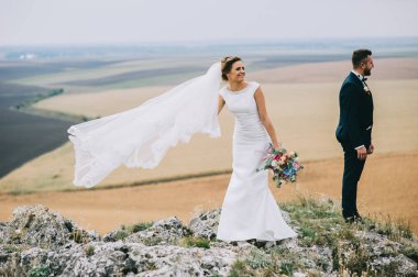 mutlu genç damat ve gelin cliff rüzgarlı gün ayakta 