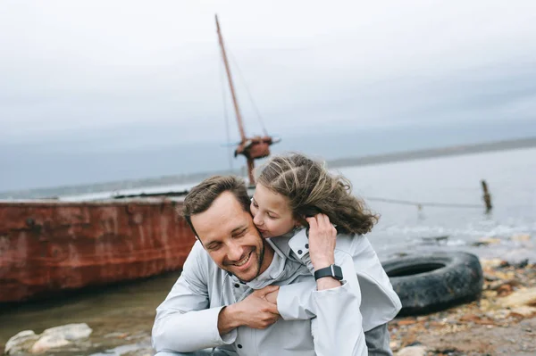 お父さんと海の近くのレインコートで娘の家族の肖像画 — ストック写真