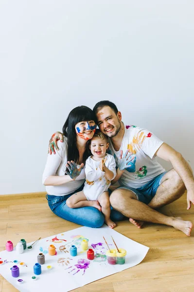 happy family and a cat painting a poster and one another with paints