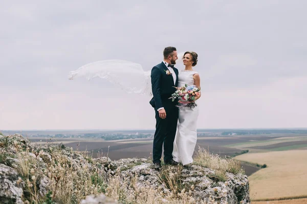 崖の上に立って美しい幸せな若い結婚式のカップル — ストック写真