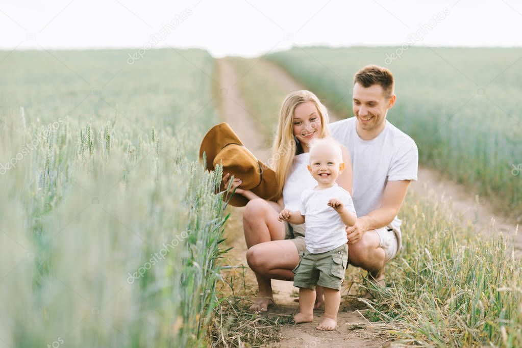 young happy family have a fun with their little baby in the field