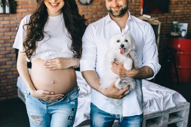 Sabahleyin yatakta yatarken bir köpek ile evli ve hamile Çift.