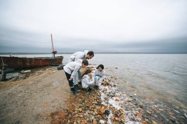mutlu genç aile bulutlu hava, deniz kenarında eğleniyor