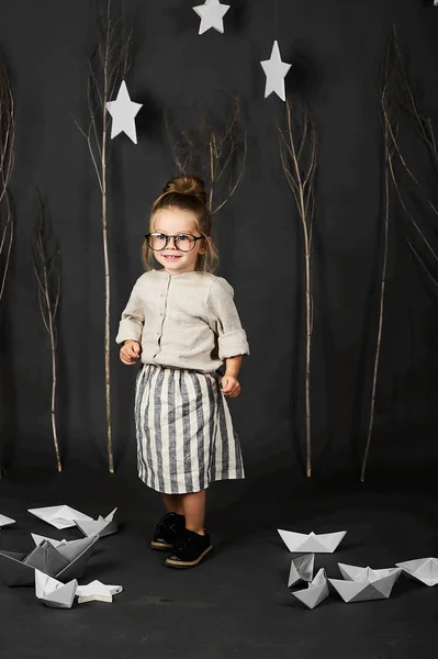 Malá Dívka Brýlemi Šedém Pozadí Hvězdami Stromy Papírové Lodě — Stock fotografie