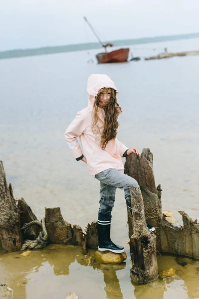 portrait  of a girl near the sea in the pink raincoat