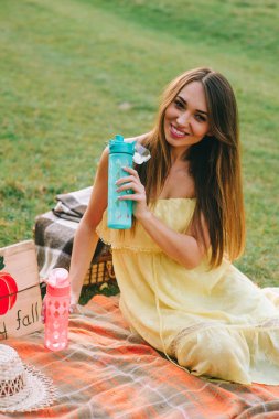 Genç güzel kadın pikniğe suyu içer