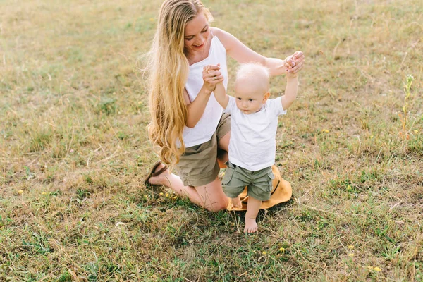 若い母はフィールドで彼女の小さな赤ちゃんと楽しい時を過す — ストック写真