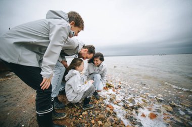mutlu genç aile bulutlu hava, deniz kenarında eğleniyor
