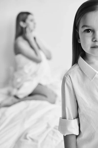 Uma bela mãe grávida e filha brincando em uma cama branca em — Fotografia de Stock