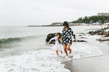 Anne ve kızı elele ve sahilde yürüyüş. Anne ve 