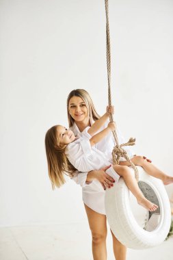 Güzel bir hamile anne kızıyla birlikte bir salıncak üzerinde çalış bir