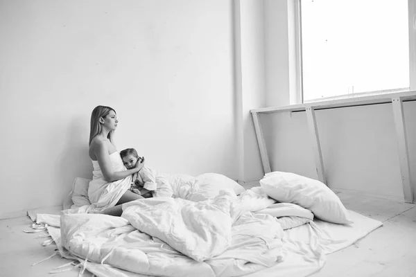 Una bella mamma incinta e figlia che gioca su un letto bianco in — Foto Stock