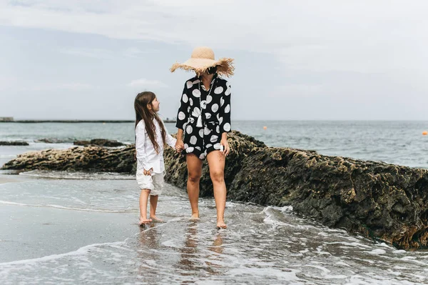 Madre e hija cogidas de la mano y caminando por la playa. Mamá y —  Fotos de Stock