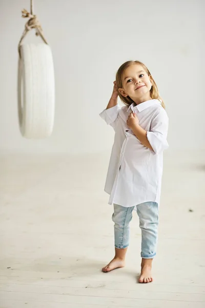 Uma linda menina brincando com um barco baloiço no r branco — Fotografia de Stock