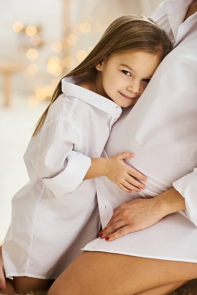 Mãe grávida feliz e sua filha se abraçam — Fotografia de Stock