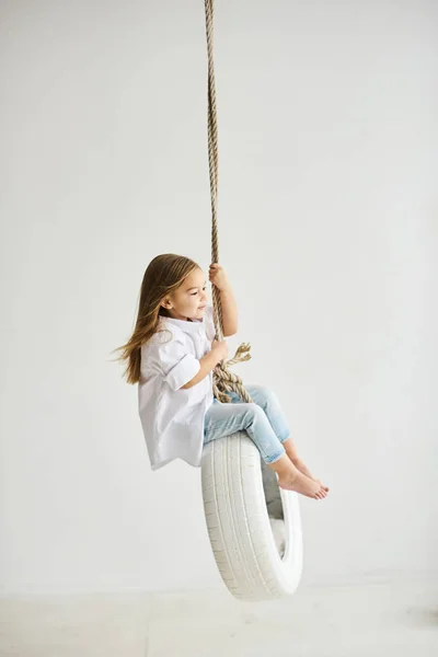 Śliczną dziewczynkę, grając z łodzi swing w biały r — Zdjęcie stockowe