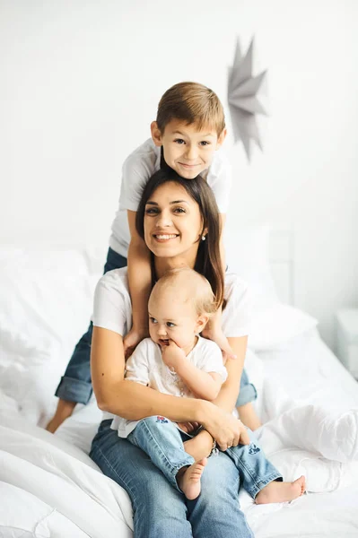 Feliz familia amorosa. madre jugando con sus hijos en la cama — Foto de Stock