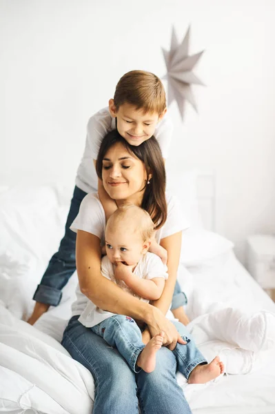 Glad kärleksfull familj. Mamma leker med hennes barn i sängen — Stockfoto