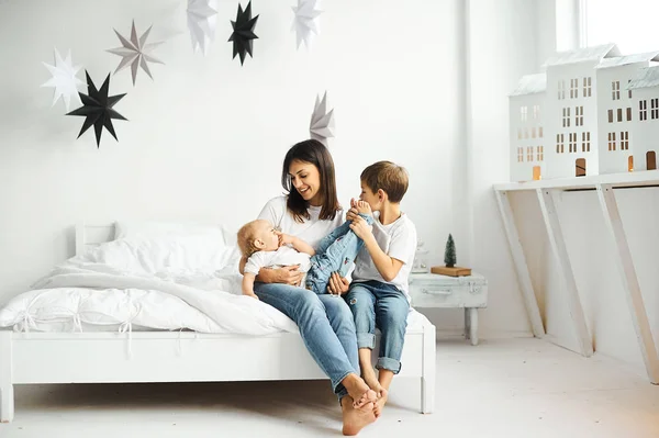 Gelukkige liefdevolle familie. moeder speelt met haar kinderen in het bed — Stockfoto